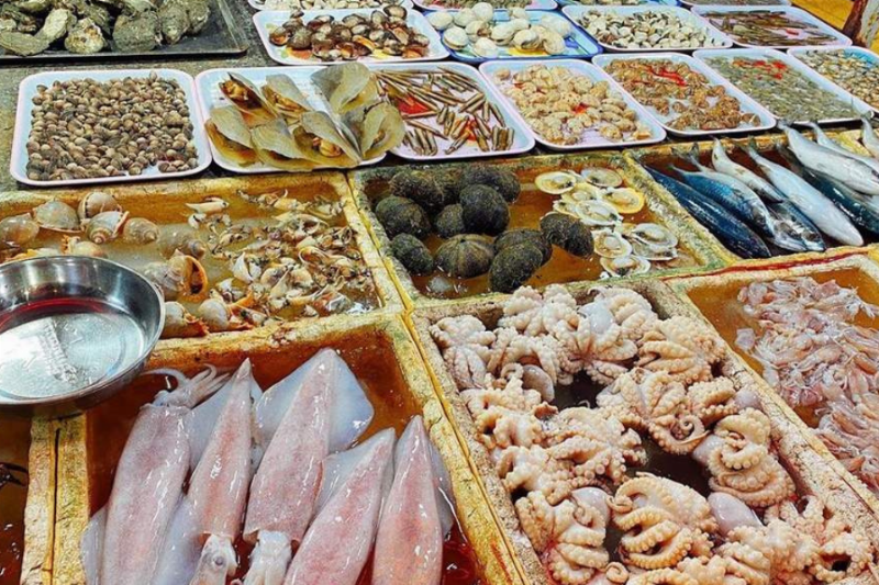 Người dân địa phương và du khách đang thưởng thức các món ăn tại khu ẩm thực nhộn nhịp của Chợ Đông Ba, thể hiện không khí sôi động